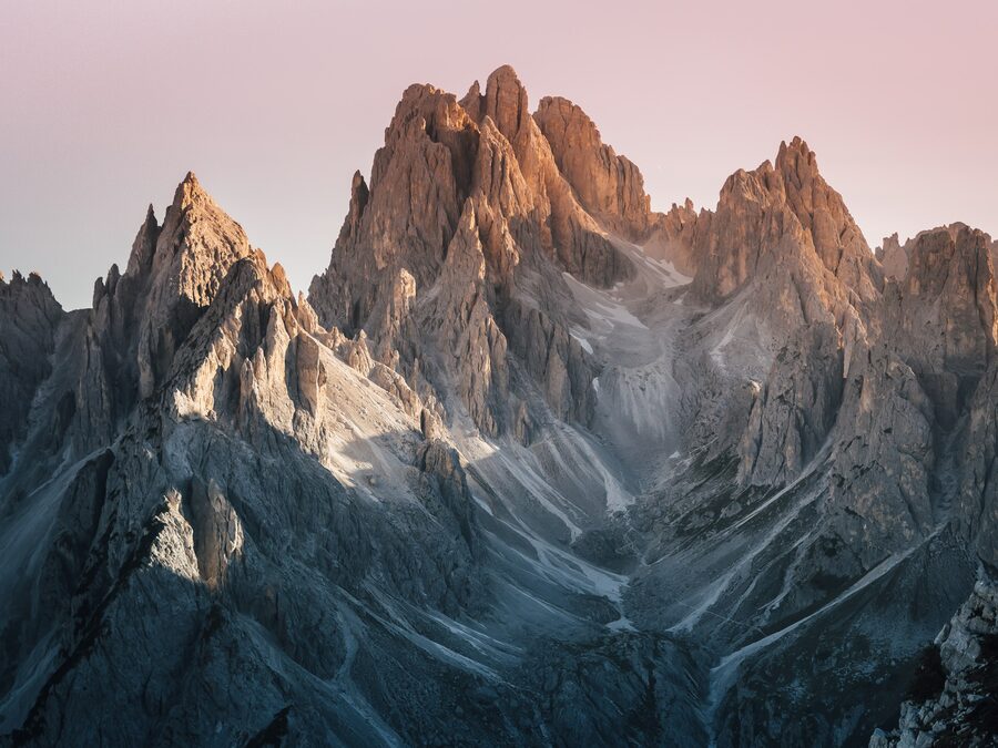 Una pared de roca enorme con algo de nieve en lo alto