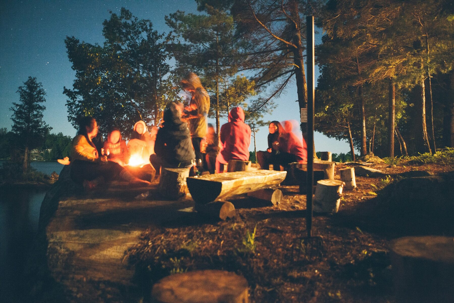 Un grupo junto al fuego entre árboles, ya de noche