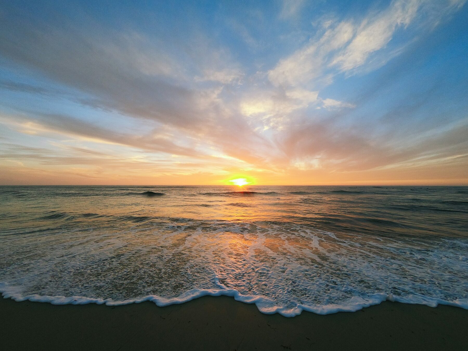El sol cayendo sobre el mar desde la orilla