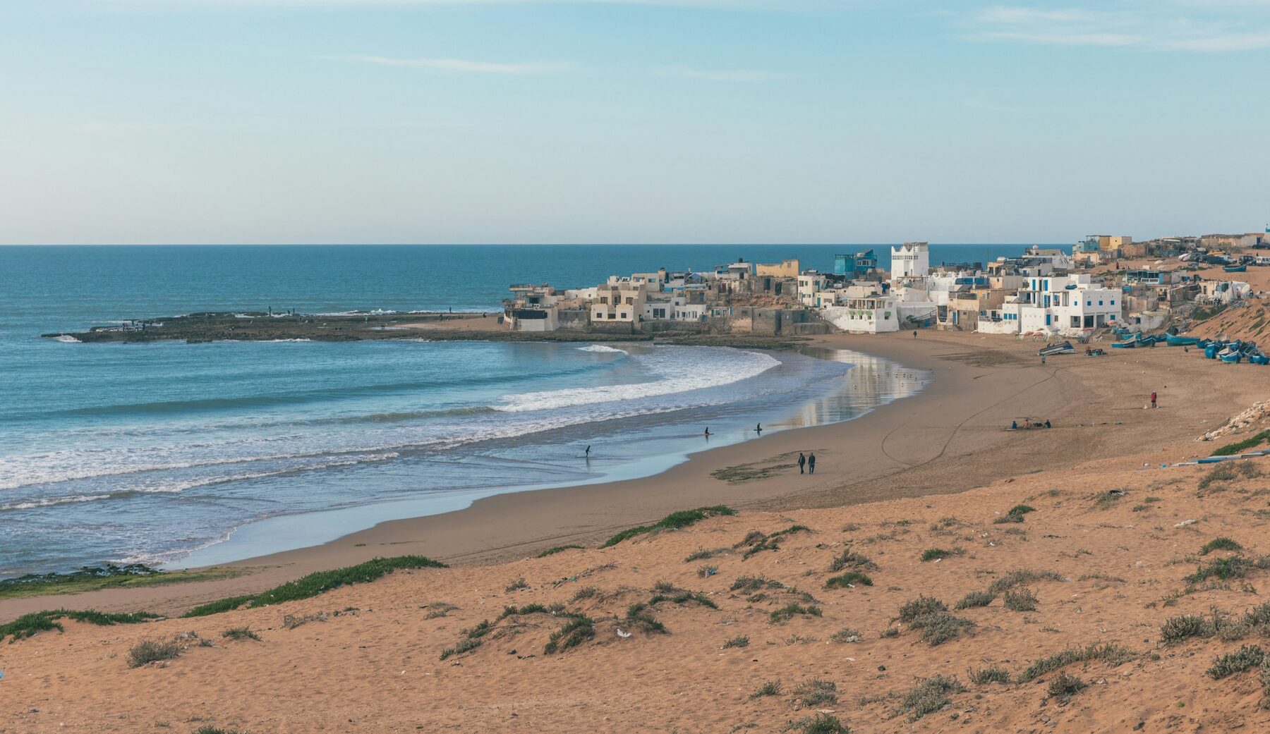 Una playa larga y abierta de Marruecos con unas pocas personas a lo lejos